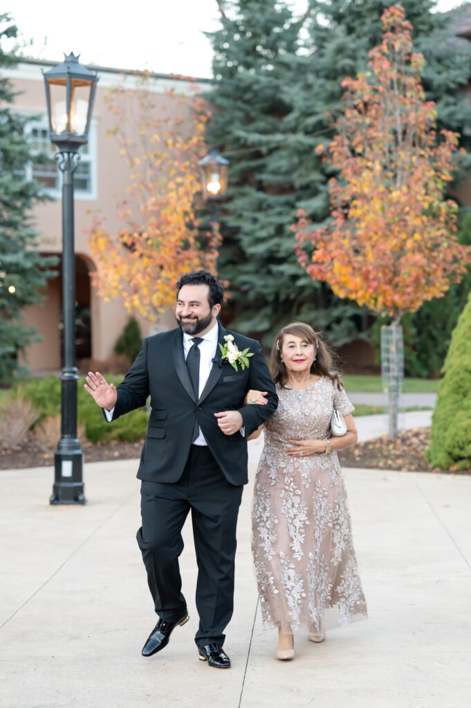 Groom walking his mom down the aisle during their wedding ceremony at The Broadmoor