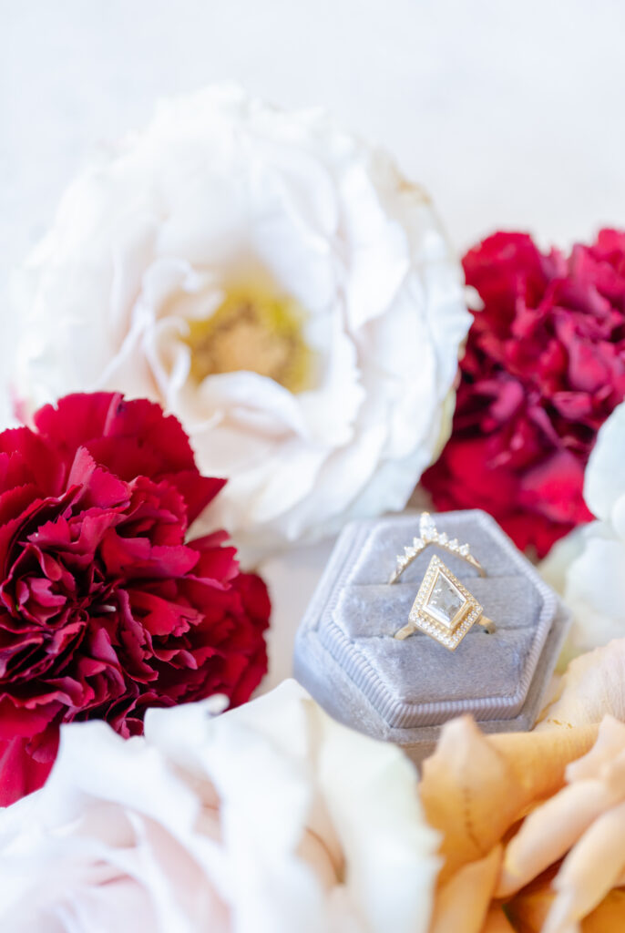 Flat lay of bridal wedding details featuring white, red, and orange florals