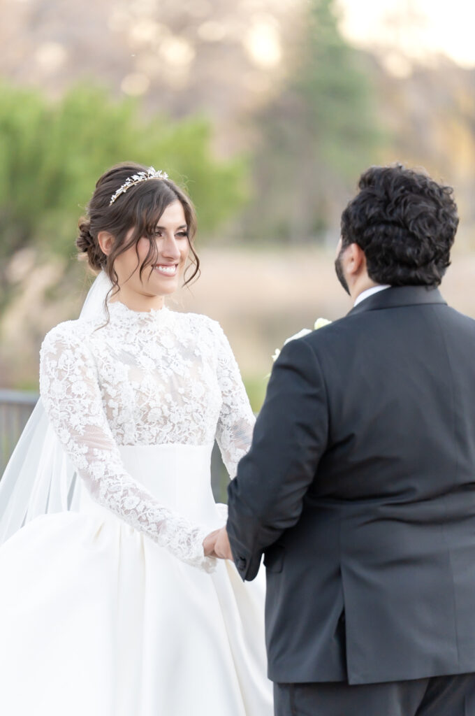 Bride holding her groom's hands and smiling at him during their winter Colorado Springs wedding, at The Broadmoor