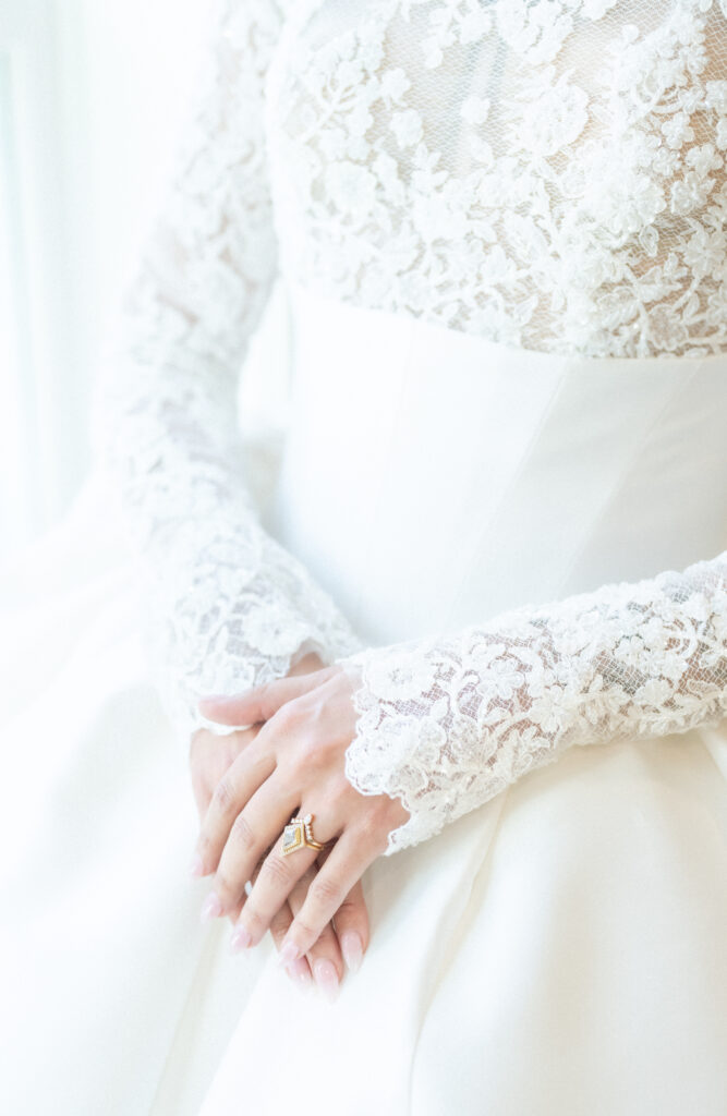Bride holding her hands together against her white dress 