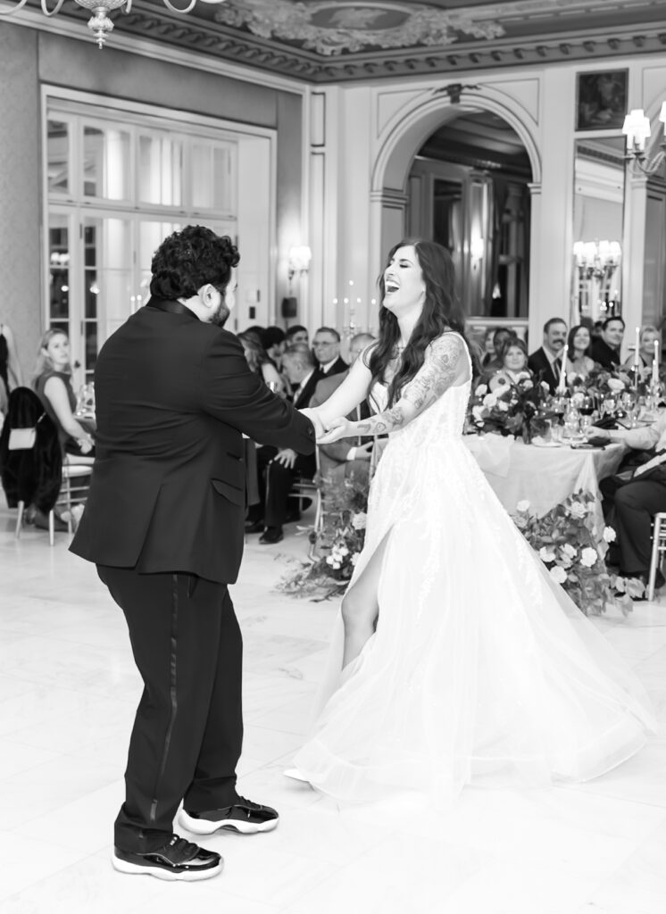 Black and white portrait of the bride and groom laughing and smiling together, during their first dance, at The Broadmoor