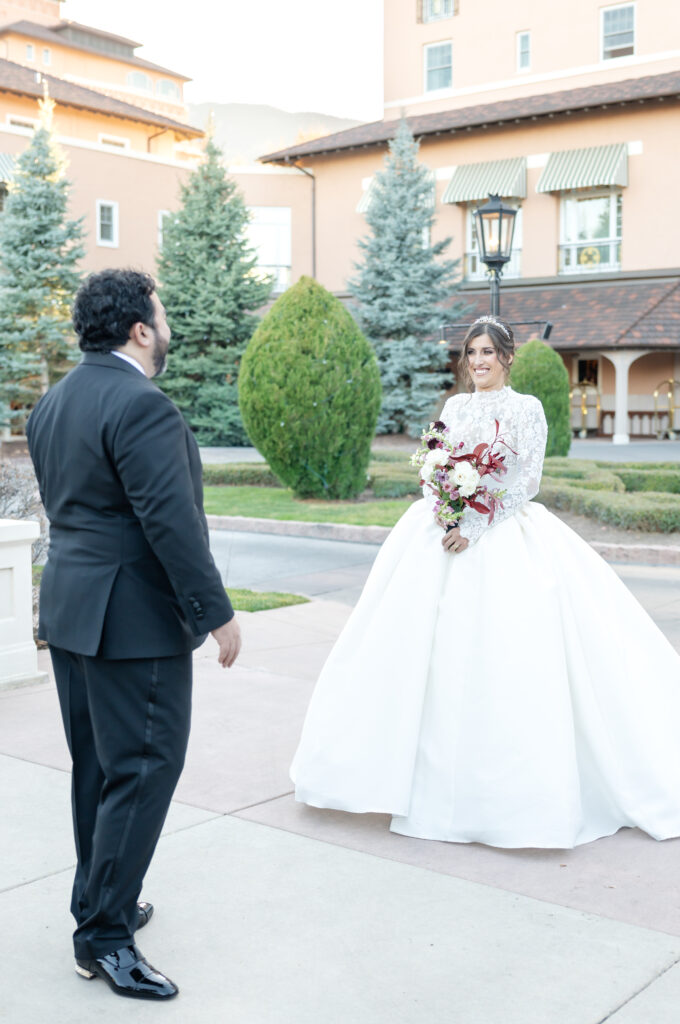 The bride and groom share their first look outside in front of the Broadmoor building in Colorado Springs on their winter wedding day