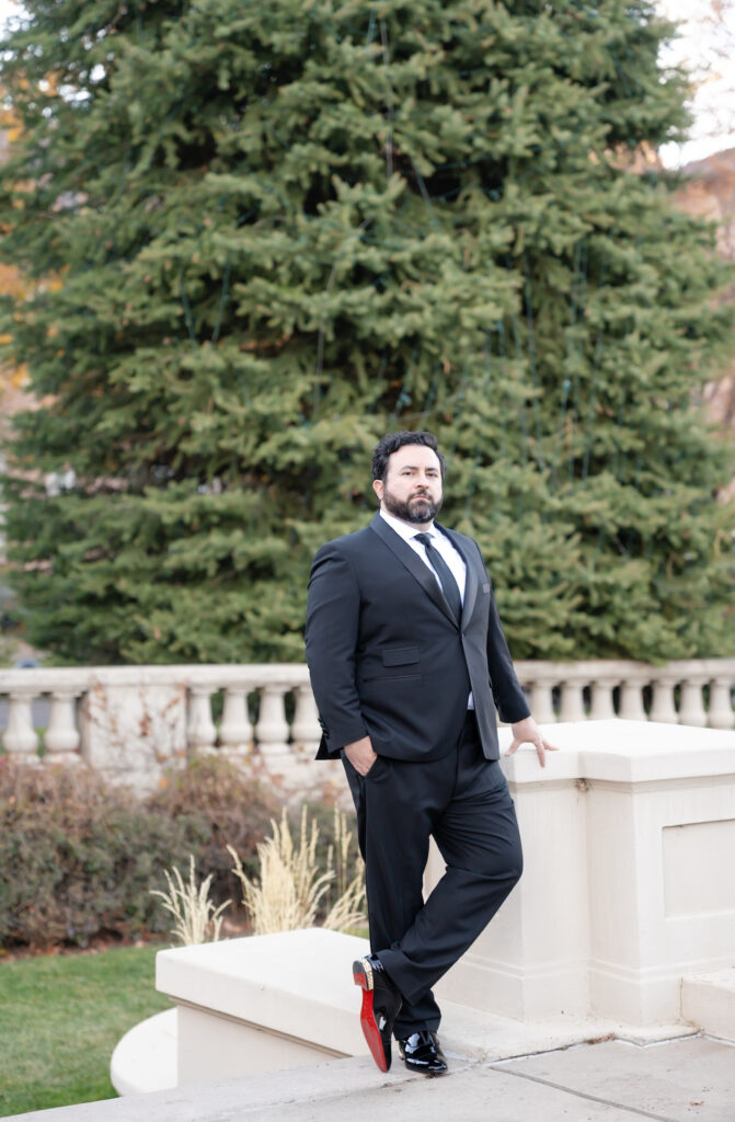Groom standing against a post, while posing for a portrait, for his winter wedding day at The Broadmoor