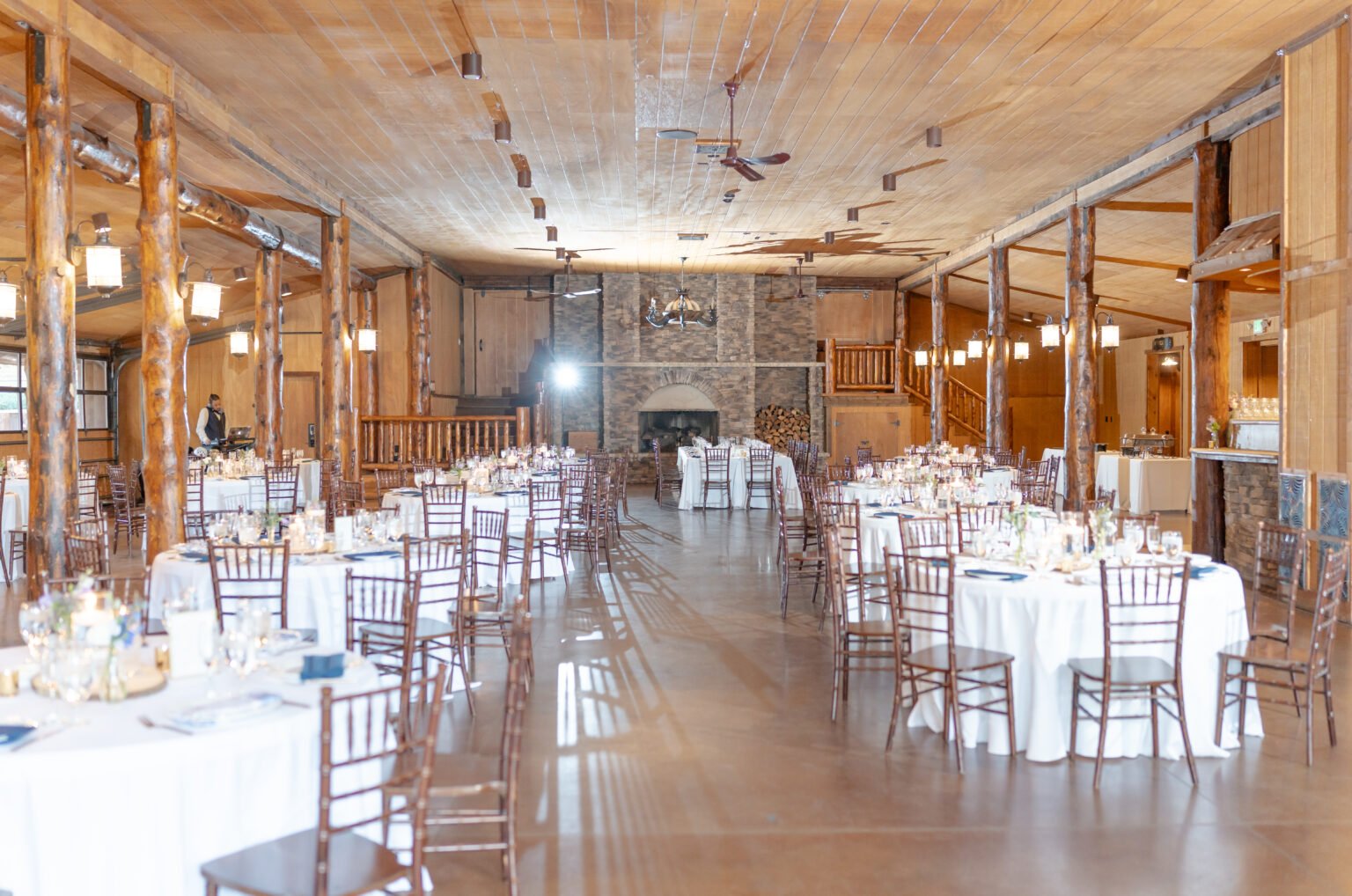 white linen on round tables and brown chairs in the spruce mountain ranch wedding reception space