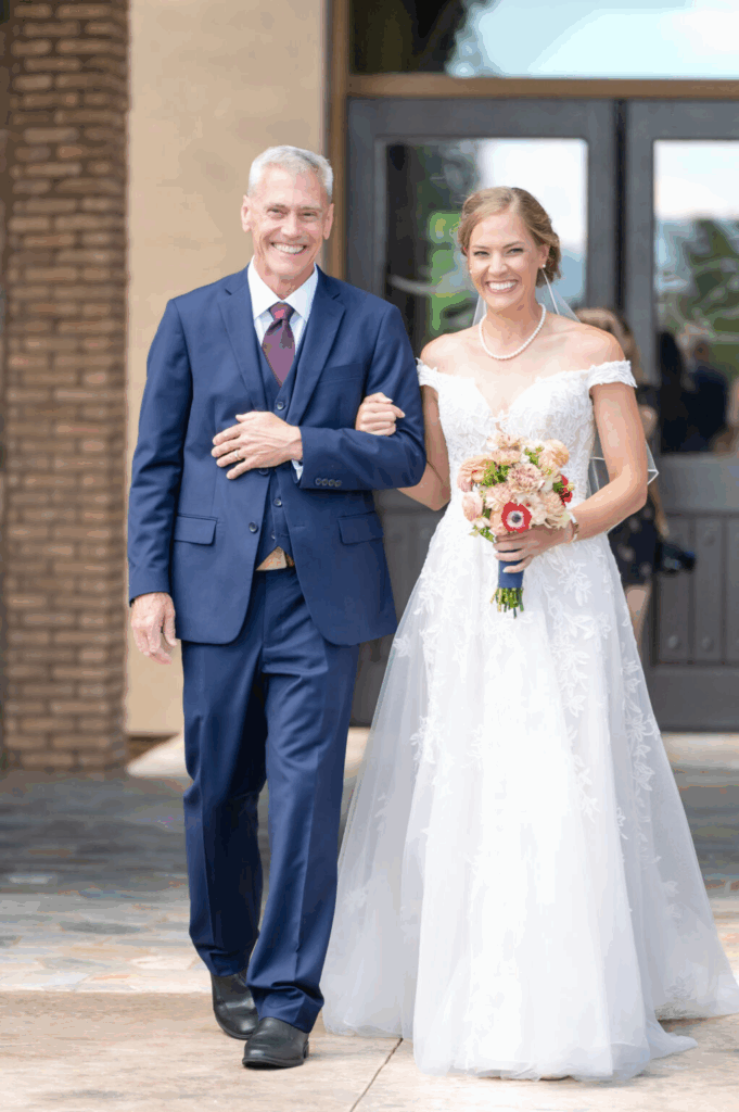 bride being walked down the aisle by an older man, she is dressed in white, photographer by whitney marshall at their outdoor wedding in colorado springs
