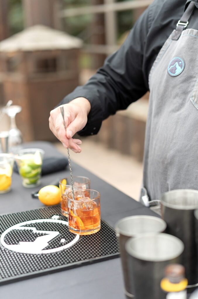 bartender mixing a drink for wedding guests at an outdoor wedding venue in colorado springs