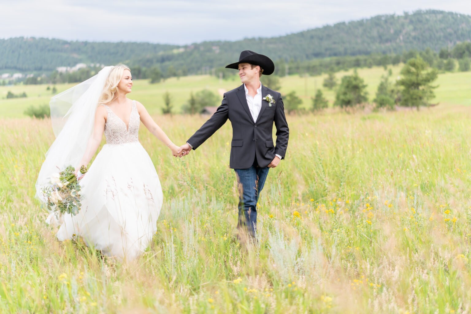 bride and groom walking in an open field during their colorado springs outdoor wedding