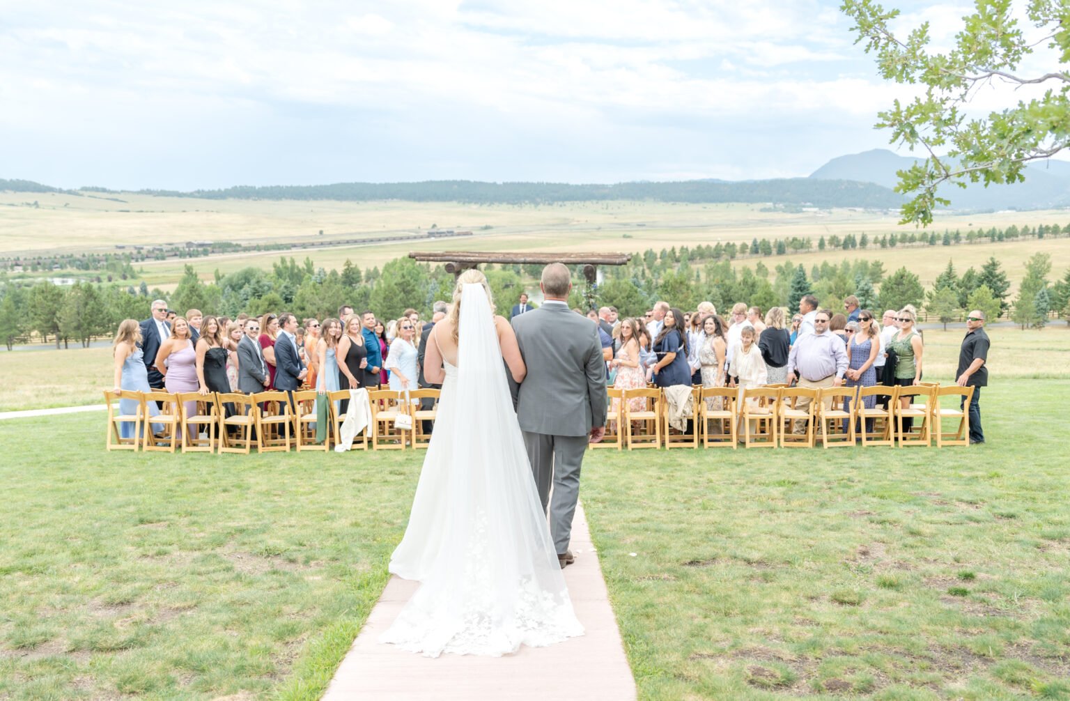bride walking down the aisle towards her groom at spruce mountain ranch, an outdoor wedding venue in colorado springs