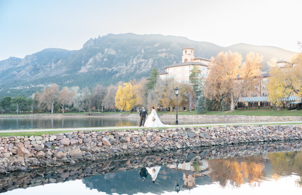 Beautiful landscape photo of the bride and groom walking along the bridge with mountain landscape behind them at The Broadmoor