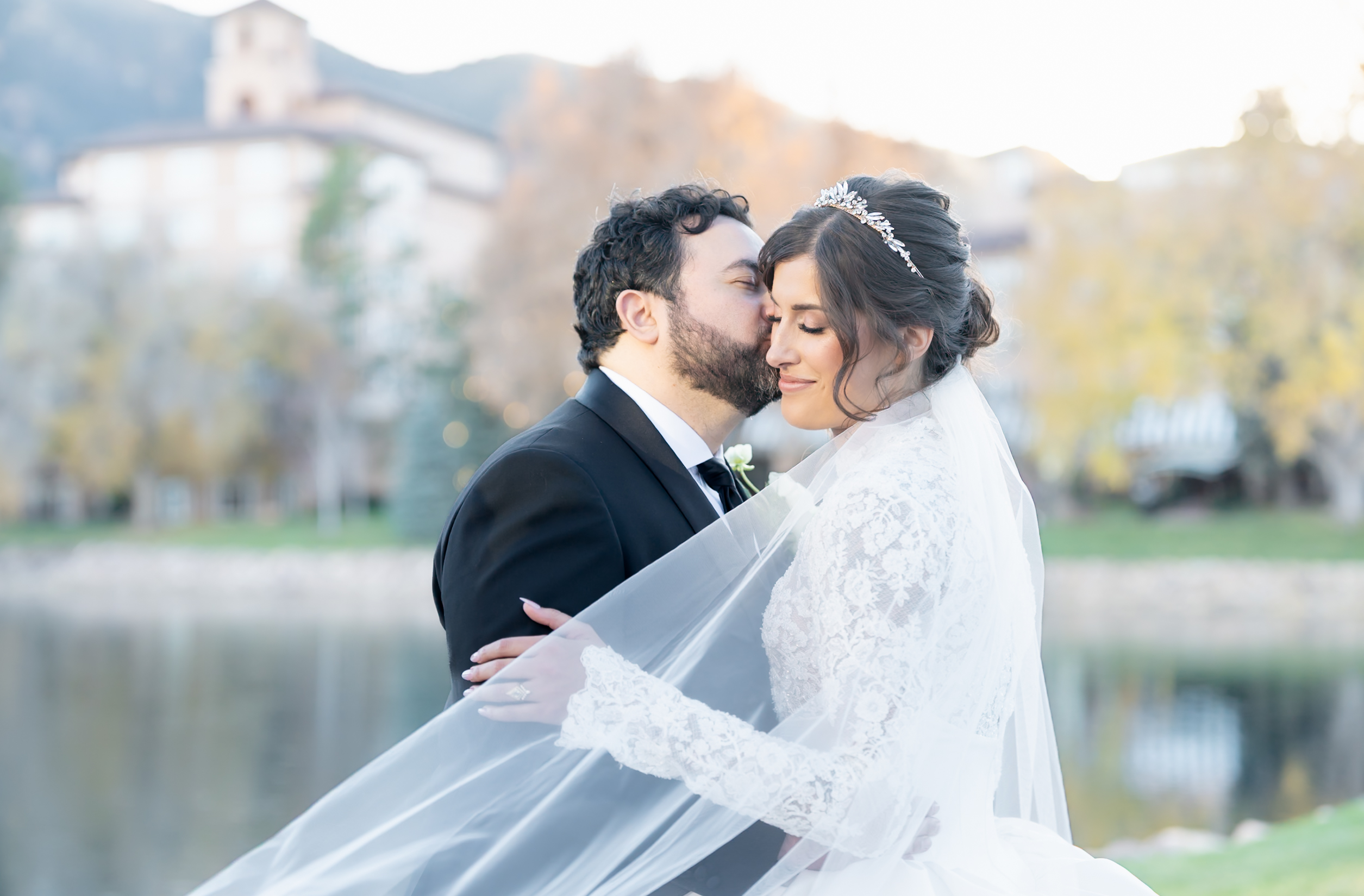 Groom giving his bride a kiss on the cheek, on their wedding day, at The Broadmoor venue located in Colorado Springs