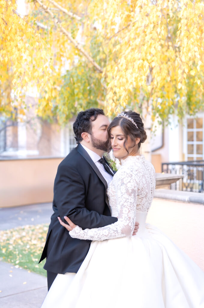 Groom giving his bride a kiss on the cheek, at The Broadmoor, an elegant winter wedding venue in Colorado Springs