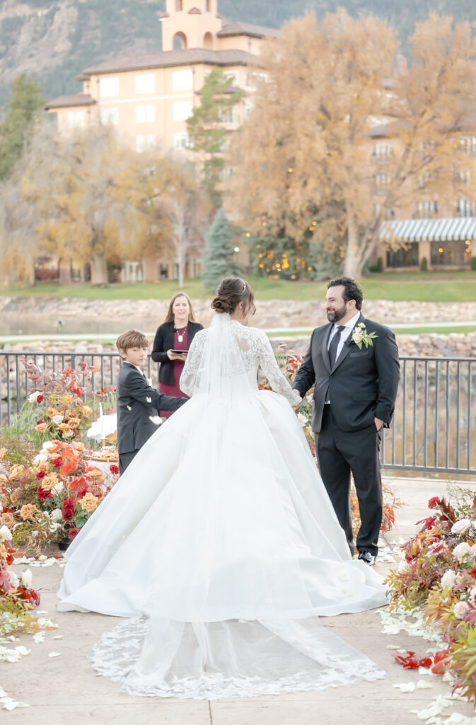 Bride holding her groom and son's hand as enter their wedding ceremony, at The Broadmoor, in Colorado Springs