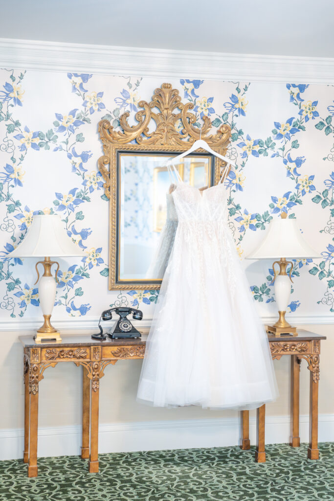 Winter wedding dress hanging against gold mirror in hallway at The Broadmoor wedding venue in Colorado Springs 