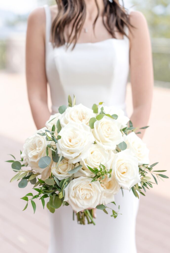 Close-up of a classic ivory rose bridal bouquet with eucalyptus and fresh greenery, photographed in soft natural light during a Colorado Springs mountain wedding.